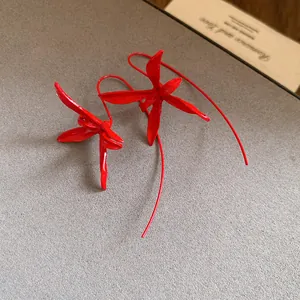 Detail view of vibrant red metal flower ear hooks with a sleek matte spray-paint finish.