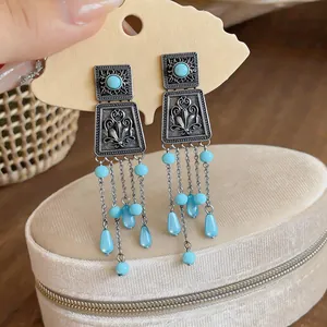 Close-up view of vintage silver-tone square tassel earrings with turquoise blue acrylic beads
