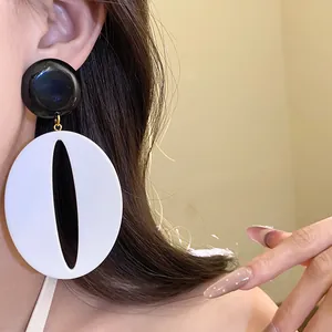 Close-up of retro black and white resin oval pendant earrings on model ear