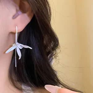 Elegant matte white spray-painted metal flower drop earrings worn by a model with dark hair