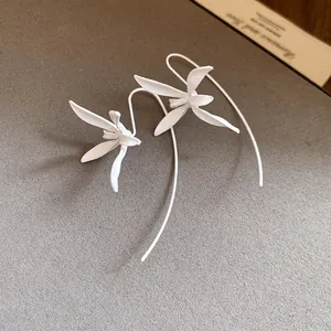 Close-up detail of elegant white painted metal flower hook earrings in minimalist style