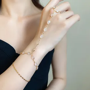 Close-up detail of an elegant vintage gold hand chain with oval resin beads on a model