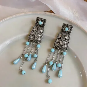 Detail view of vintage silver square embossed stud earrings featuring light blue bead tassels