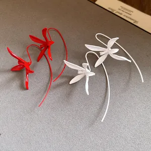 Detail of red and white orchid-shaped painted metal ear hooks on textured background