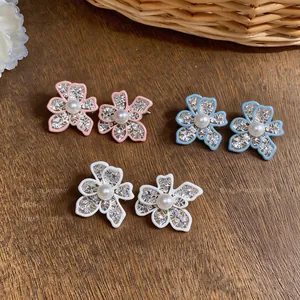 Detailed view of hollow flower stud earrings with pearls in pink, blue, and white colors