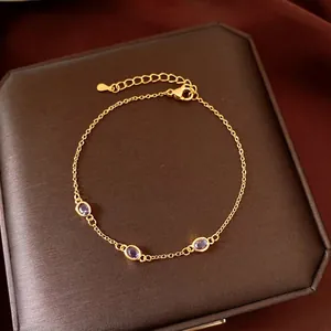 Elegante bracciale a catena dorata con tre zirconi viola ovali su portagioie