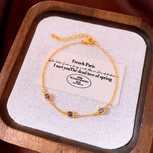 Bracciale vintage dorato con tre zirconi ovali viola su tela bianca e vassoio legno