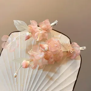 Macro view showing detail of pink fabric flower hair clips with pearls on white fan