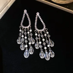 Detailed close-up of silver needle zircon tassel earrings with crystal drops and pearls.