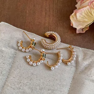 Eleganti orecchini a cerchio con perle placcati oro 18k e zirconi su un cuscino per gioielli