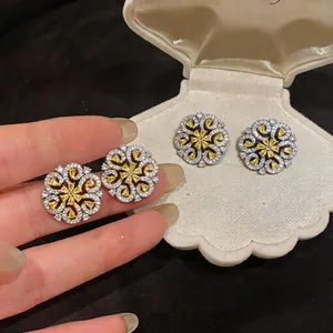 Detailed macro view of 18K gold plated zircon flower stud earrings in a cream shell box.