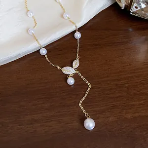 Primo piano di una collana a foglia placcata in oro 18 carati con zirconi e perle eleganti