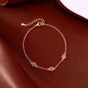 Dettaglio di un bracciale vintage dorato con tre zirconi viola su sfondo di seta
