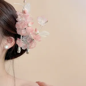 Macro detail view showing a soft pink fabric flower hair clip with pearls in hair