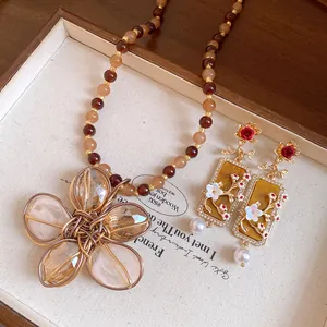 Dettaglio di un set collana vintage con fiori di perline e orecchini rettangolari.