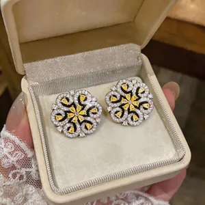 Close-up detail of elegant yellow teardrop zircon flower earrings in a cream box