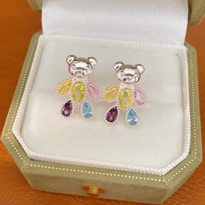 Close-up of bear-shaped stud earrings with vibrant colorful zircon stones in a gift box.