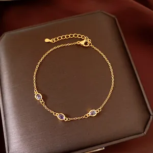 Dettaglio di un bracciale a catena dorata con tre eleganti zirconi viola di forma ovale.