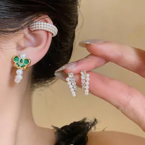 Primo piano di eleganti orecchini placcati oro 18k con perle e dettagli in smalto