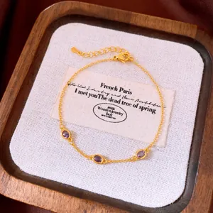 Vista dettagliata del bracciale vintage dorato con tre zirconi viola su base in tela bianca