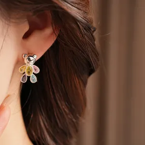 Detailed close-up of a silver teddy bear earring with colorful zircon stones worn on ear