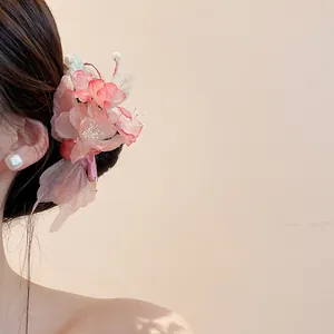 Close-up of elegant pink fabric flower hair clip with pearls worn by an Asian model