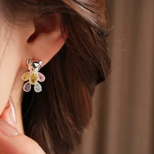 Close-up of a cute silver teddy bear stud earring with colorful teardrop zircon stones.