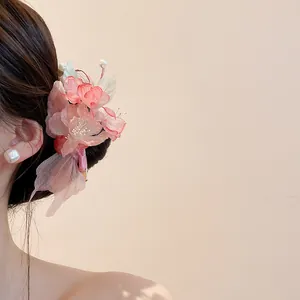 Close-up of elegant pink fabric flower hair clip with pearl accents worn on model's hair