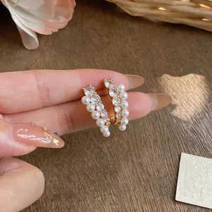 Primo piano di eleganti orecchini placcati oro 18k con perle e zirconi scintillanti