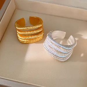 Close-up of elegant multi-layer textured open rings in 18k gold and silver finish