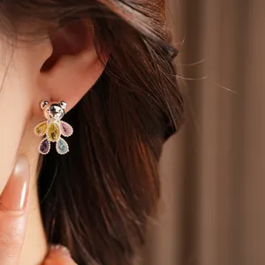 Close-up macro detail of colorful zircon teddy bear stud earring worn on person's ear