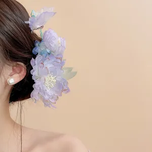 Close-up of an elegant purple fabric flower hair clip with pearl accents on a model