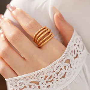 Macro detail of a textured 18k gold plated multi-layer spiral ring worn on finger
