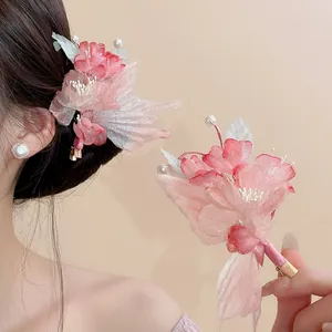 Detailed close-up of a pink fabric flower hair clip with elegant pearl embellishments