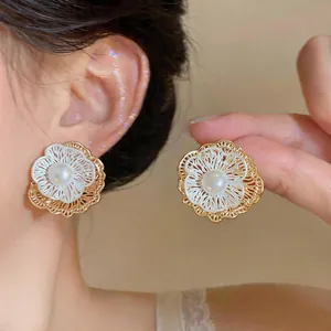 Detailed view of French vintage hollow flower earrings with central pearl on the ear.