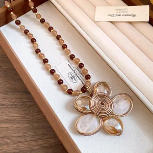 Vista dettagliata di una collana di perline vintage con un grande pendente a fiore intrecciato.