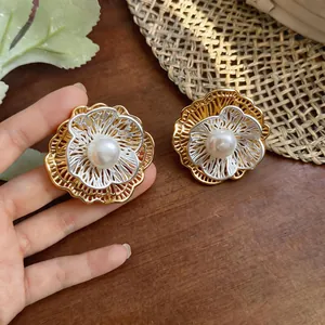 Detail of French vintage bicolored hollow flower earrings with central white pearls