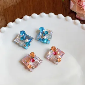 Vista detallada de pendientes cuadrados de cristal y perlas en tonos azul y rosa