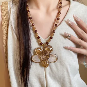 Dettaglio di una collana di perle vintage con ciondolo a fiore in cristallo avvolto.