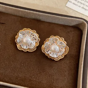 Close-up of vintage-style hollow flower earrings with central white pearls