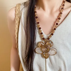 Dettaglio di una collana vintage con perline e un grande ciondolo a forma di fiore