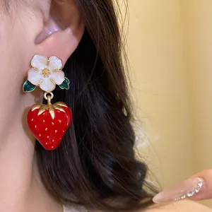 Close-up of sweet enamel strawberry and white flower drop earrings on model