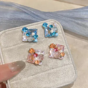 Primer plano de elegantes pendientes de cristal cuadrado con perlas en joyero.
