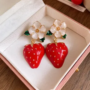 Detailed view of sweet enamel flower and red strawberry drop earrings in a pink gift box