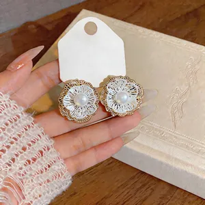 Detailed close-up of French vintage openwork flower earrings with central pearl detail