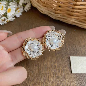 Detailed close-up of French vintage hollow flower stud earrings with central pearls