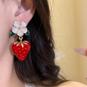 Detailed close-up of sweet enamel flower and strawberry drop earring on ear