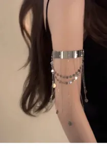 Dettaglio di un bracciale da braccio in argento con nappe di paillettes su braccio modella