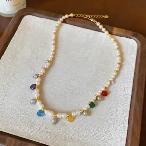 Close-up of a handmade pearl necklace with vibrant glass charms on a wooden tray