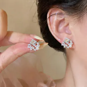 Close-up of elegant silver stud earrings with rhombus zircon, butterfly motif and pearl